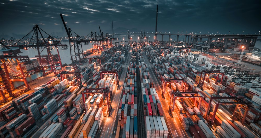Container port with stacked shipping containers and cranes
